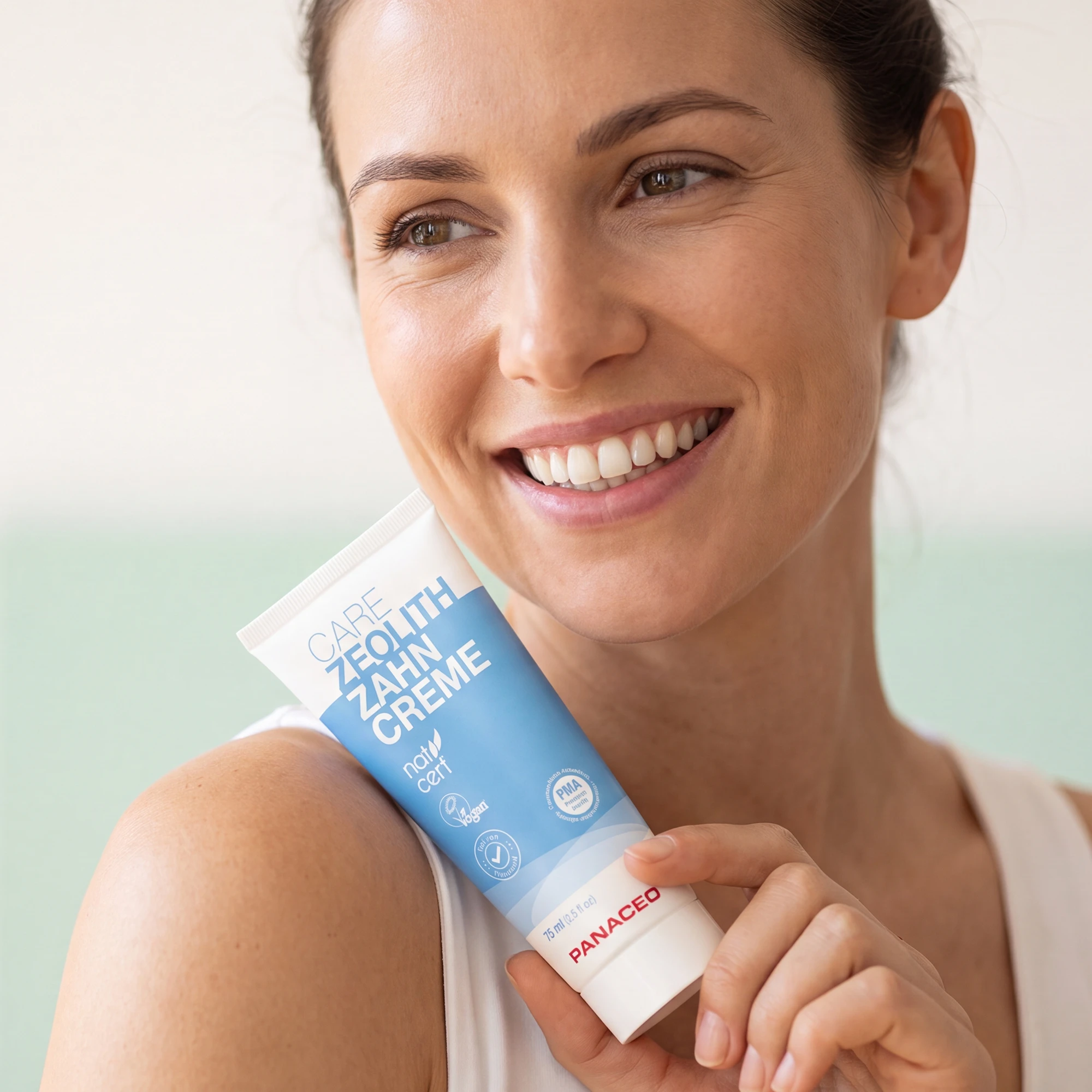PANACEO Care Zeolite Toothpaste 75 ml – natural dental care for fresh breath Smiling woman holding PANACEO Care Zeolite Toothpaste 75 ml – fluoride-free, vegan toothpaste with PMA zeolite for natural oral care