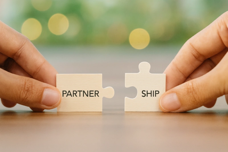 PANACEO Affiliate-Partnerschaft – gemeinsam gesund wachsen durch natürliche Produkte. Zwei Hände verbinden zwei hölzerne Puzzleteile – Symbol für Vertrauen und erfolgreiche Partnerschaft im PANACEO Affiliate-Programm für Gesundheitsprodukte.