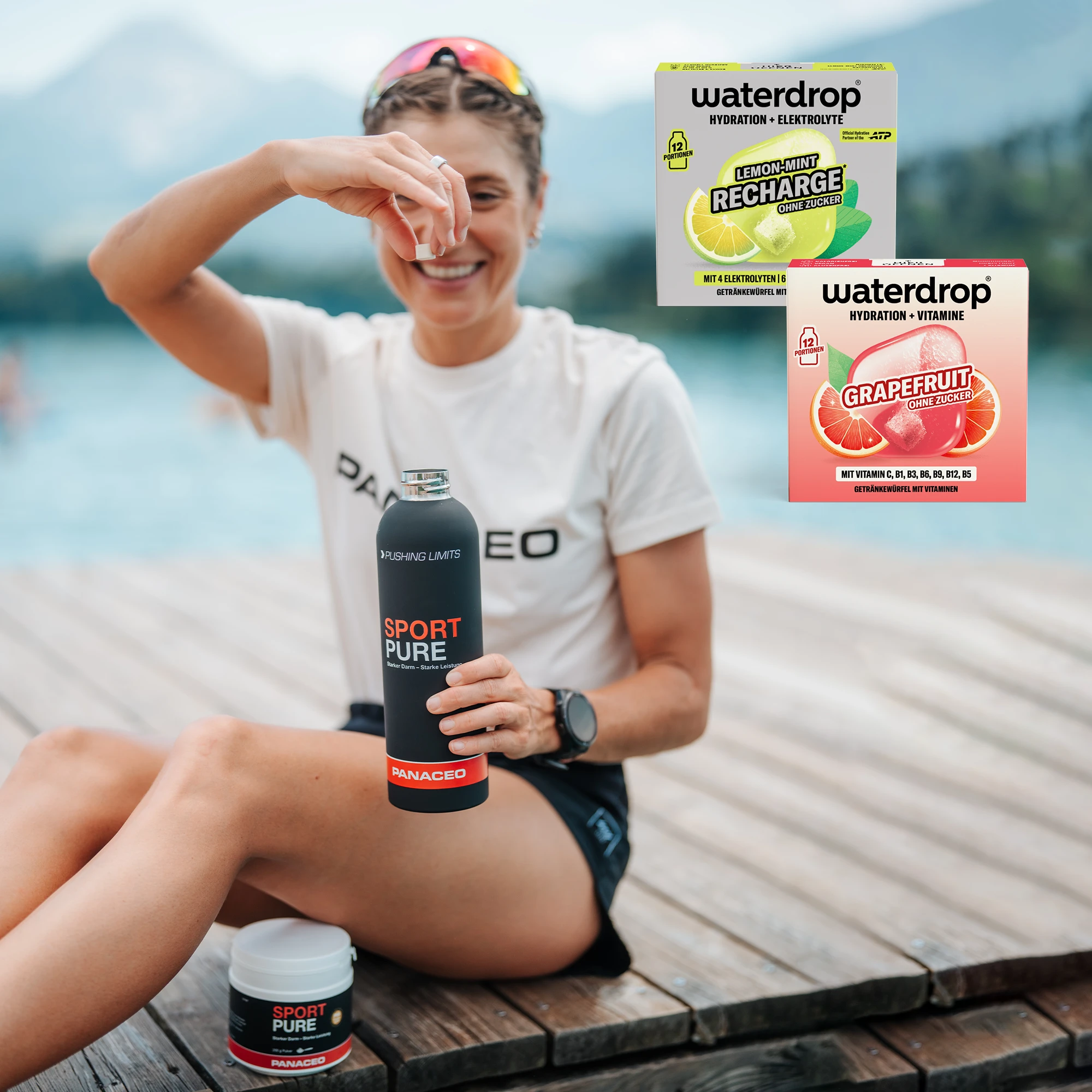 Sportlerin sitzt am See und gibt einen Getränkewürfel in die PANACEO Sport Pure Flasche; eingeblendet sind Waterdrop Lemon-Mint Recharge und Grapefruit.