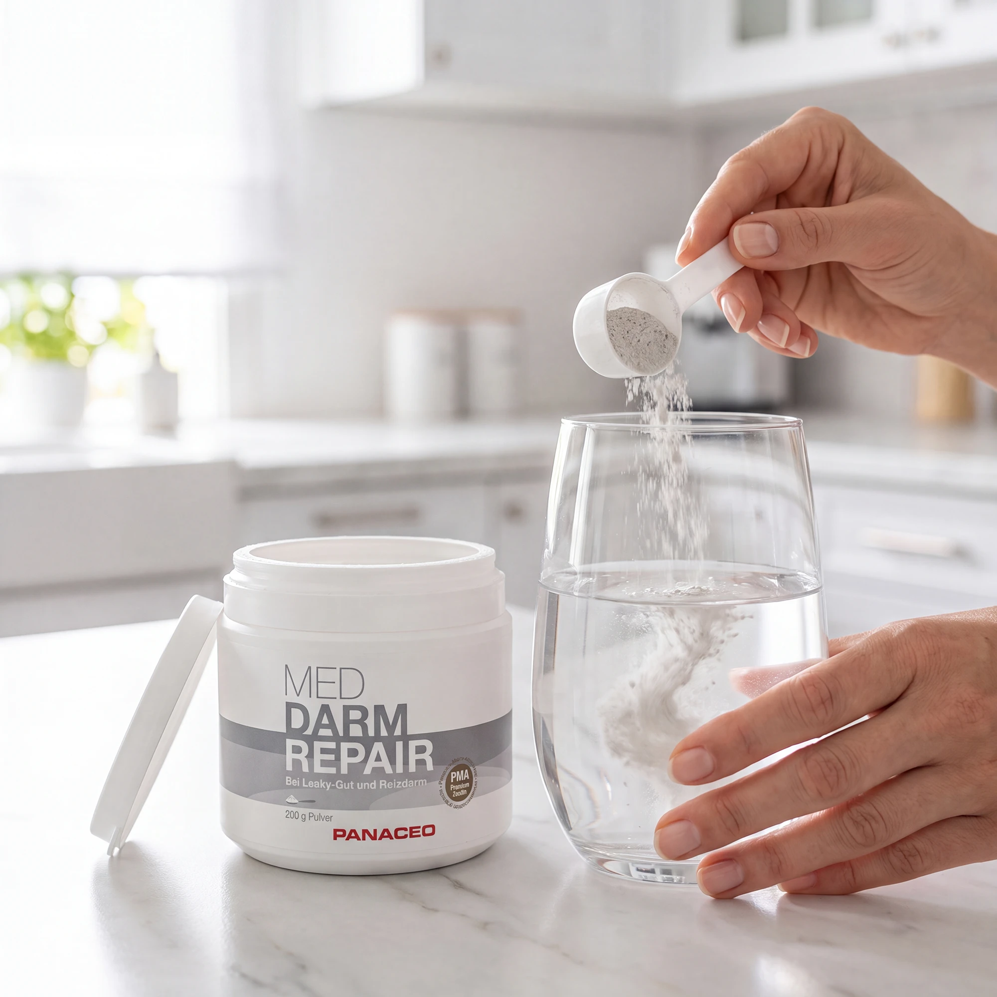PANACEO MED Darm Repair Pulver wird mit Messlöffel in ein Glas Wasser eingerührt Hand dosiert PANACEO MED Darm Repair Pulver mit Messlöffel in ein Glas Wasser in heller Küche