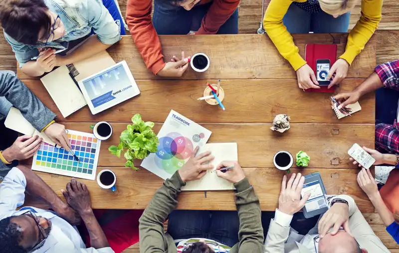 Ein kreatives Team bei einem Meeting am Holztisch – Symbol für Zusammenarbeit, Markenentwicklung und Innovation bei PANACEO.